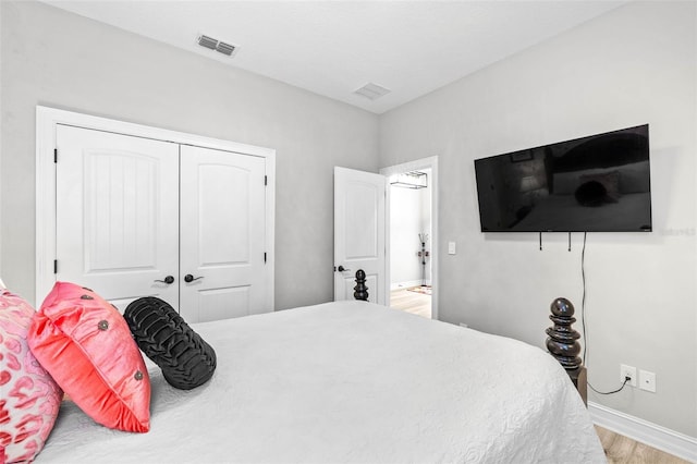 bedroom with wood finished floors, baseboards, and a closet