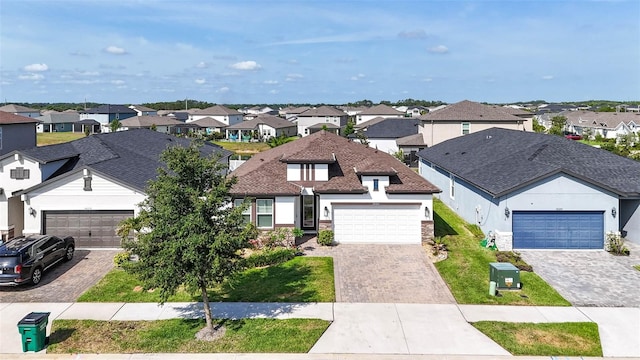 traditional home with a residential view, decorative driveway, a garage, and a front yard
