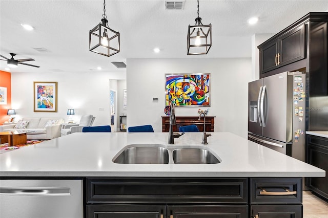 kitchen with a sink, appliances with stainless steel finishes, light countertops, ceiling fan, and open floor plan