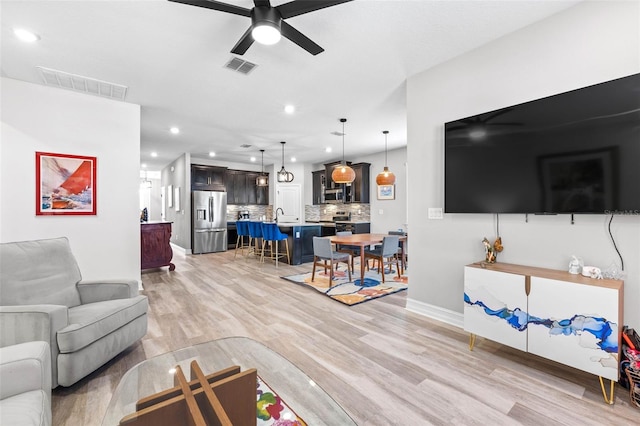 living room featuring ceiling fan, recessed lighting, light wood-style floors, and baseboards