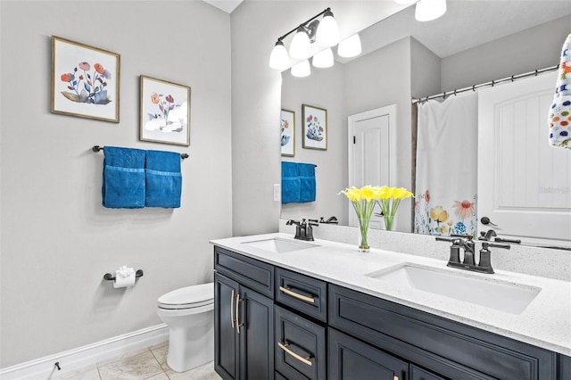 bathroom featuring toilet, baseboards, and double vanity