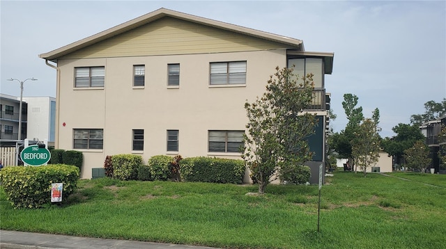 view of side of property featuring stucco siding and a lawn
