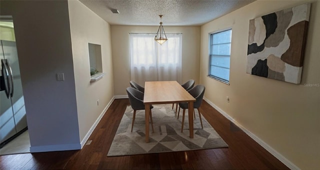 dining room featuring plenty of natural light, a textured ceiling, baseboards, and wood finished floors