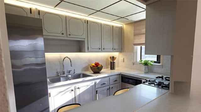kitchen featuring a sink, backsplash, stainless steel appliances, and light countertops