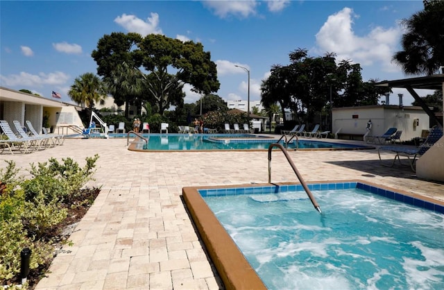 community pool with a hot tub and a patio