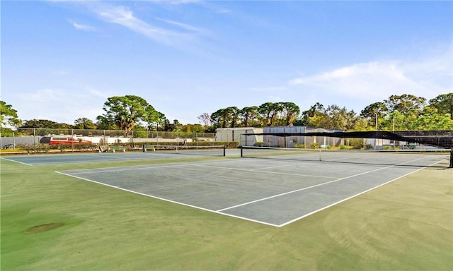 view of tennis court featuring fence and community basketball court