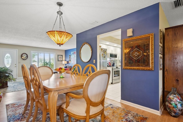 9018 39th Ln N Unit 5, Pinellas Park, FL 33782 - dining room with a textured ceiling, baseboards, and light wood finished floors