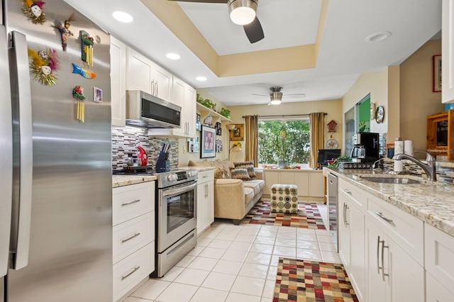 9018 39th Ln N Unit 5, Pinellas Park, FL 33782 - kitchen featuring appliances with stainless steel finishes, a ceiling fan, a sink, decorative backsplash, and white cabinetry
