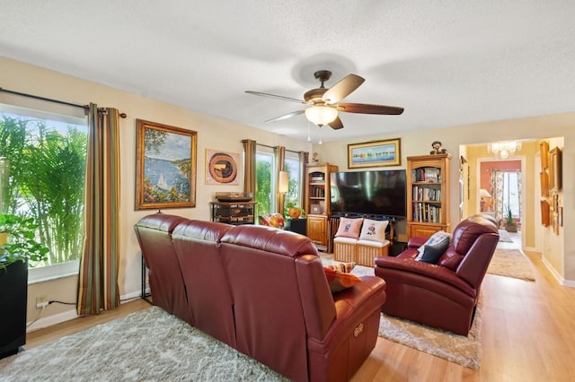 9018 39th Ln N Unit 5, Pinellas Park, FL 33782 - living area with light wood-style flooring, a chandelier, a ceiling fan, a textured ceiling, and baseboards