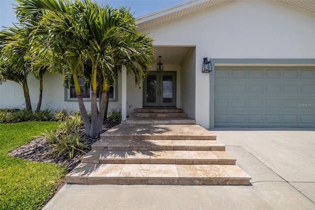 view of exterior entry featuring french doors, stucco siding, and an attached garage