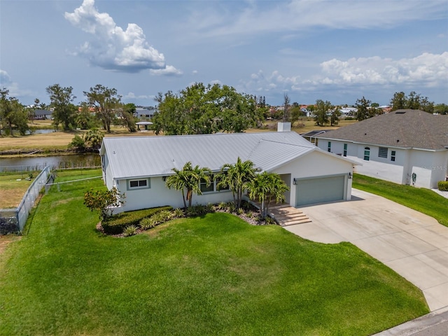 ranch-style house featuring a water view, concrete driveway, metal roof, and a garage