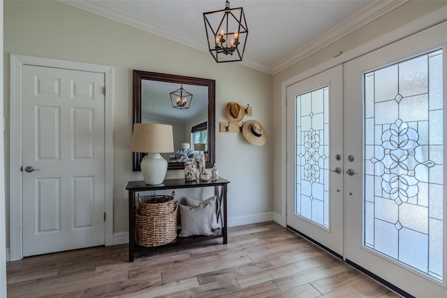 foyer with a chandelier, french doors, light wood finished floors, ornamental molding, and baseboards
