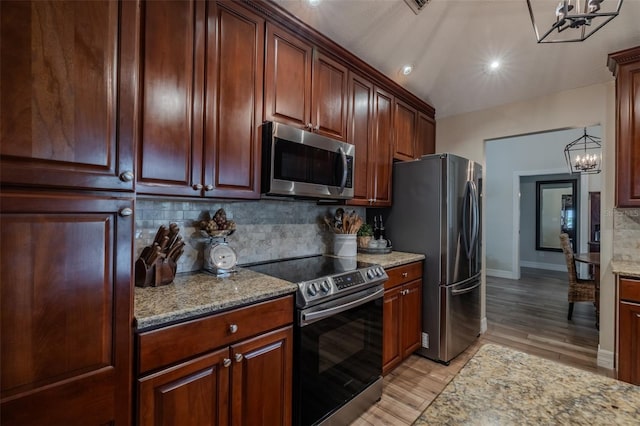 kitchen featuring stainless steel appliances, a chandelier, decorative backsplash, light wood-style floors, and light stone counters