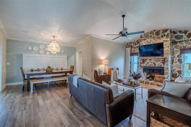 living room featuring ceiling fan, wood finished floors, a fireplace, crown molding, and plenty of natural light