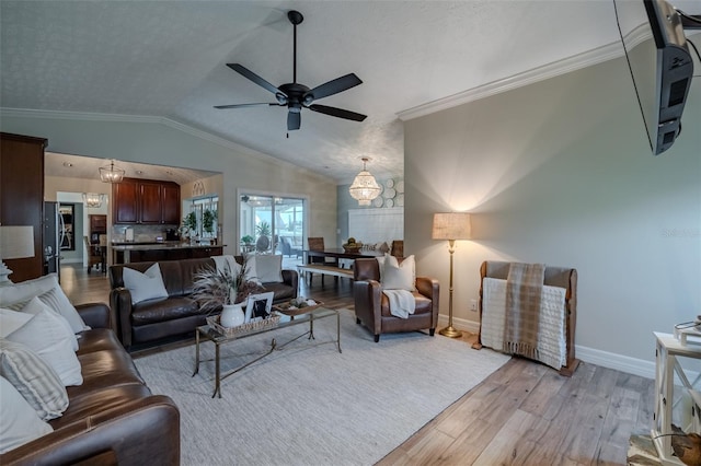 living area featuring light wood-style flooring, baseboards, ceiling fan, lofted ceiling, and ornamental molding