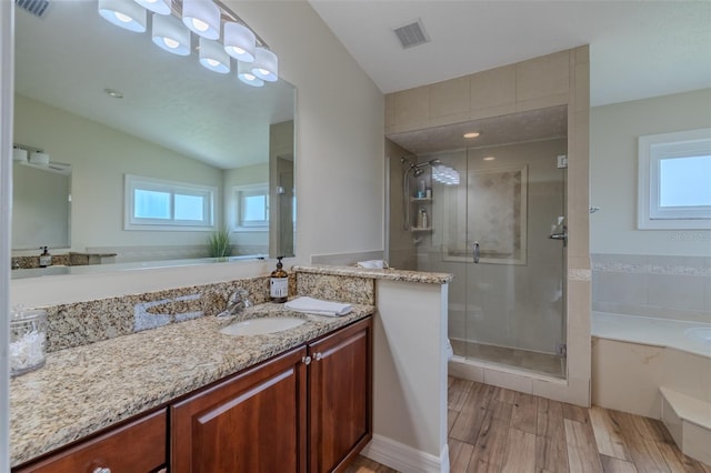 full bathroom with wood finished floors, a shower stall, vanity, a garden tub, and vaulted ceiling