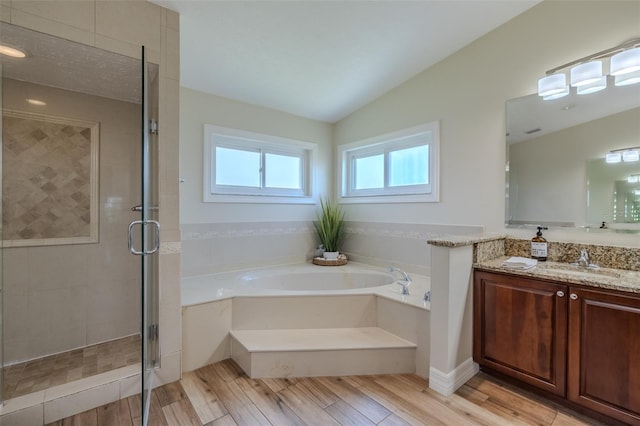 bathroom with a bath, vaulted ceiling, a shower stall, vanity, and wood finished floors