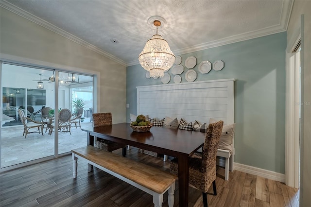 dining room featuring a chandelier, wood finished floors, crown molding, and baseboards