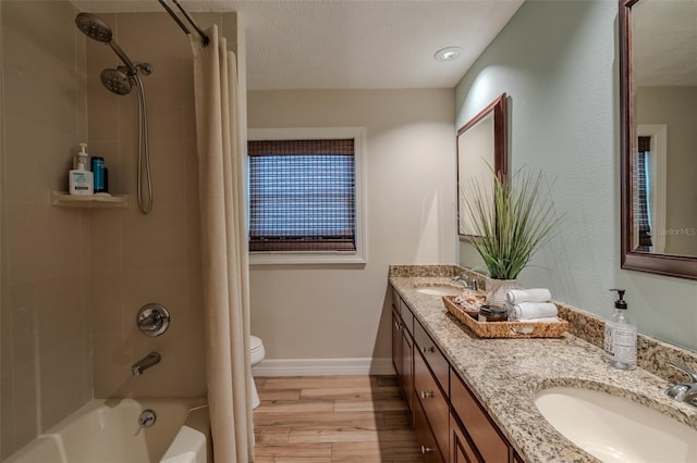 full bathroom featuring wood finished floors, shower / bath combo with shower curtain, toilet, baseboards, and double vanity