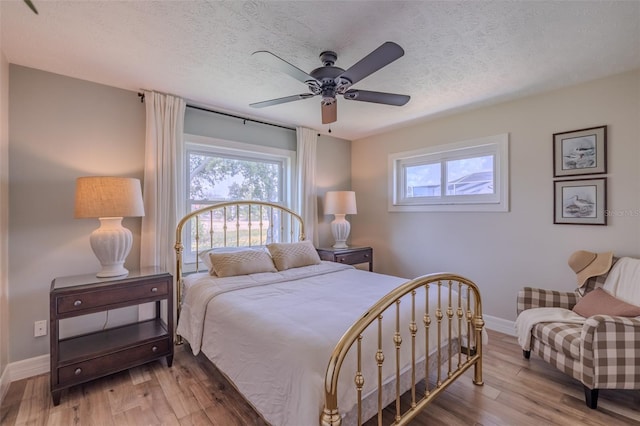 bedroom with baseboards, wood finished floors, a textured ceiling, and a ceiling fan