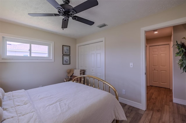 bedroom with wood finished floors, baseboards, a closet, a textured ceiling, and ceiling fan
