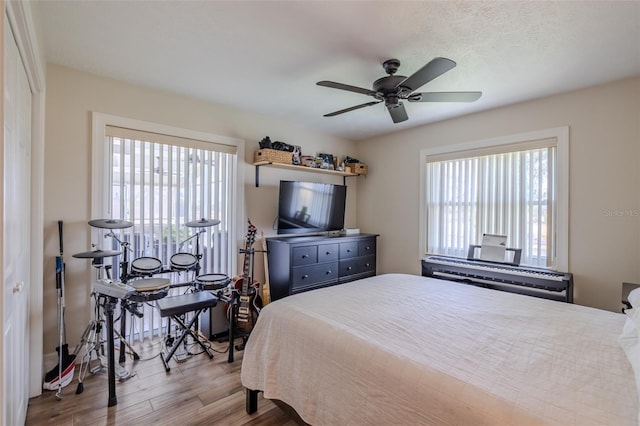 bedroom featuring multiple windows, wood finished floors, and a ceiling fan