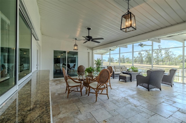 sunroom featuring a ceiling fan, outdoor lounge area, and vaulted ceiling