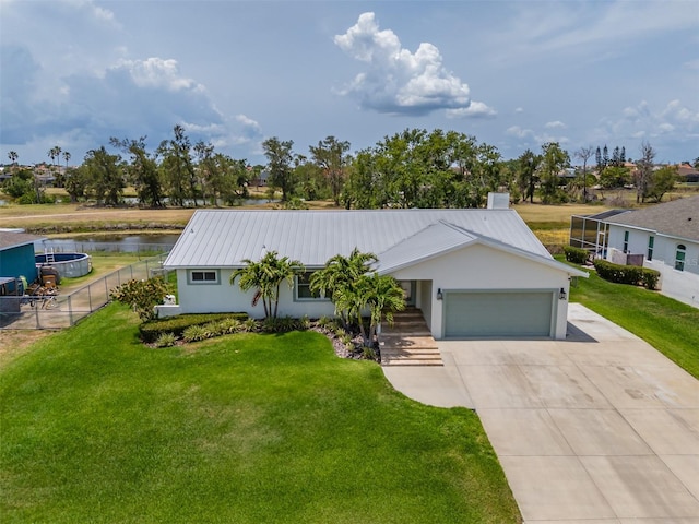 single story home featuring an attached garage, driveway, metal roof, a water view, and stucco siding