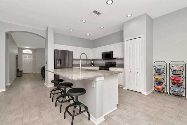 2823 Banyan Hill Ln, Land O Lakes, FL 34639 - kitchen with a sink, black appliances, white cabinets, arched walkways, and light stone counters