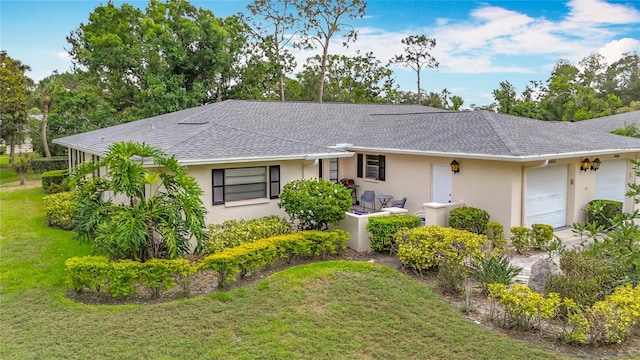 single story home with a shingled roof, a garage, stucco siding, and a front yard