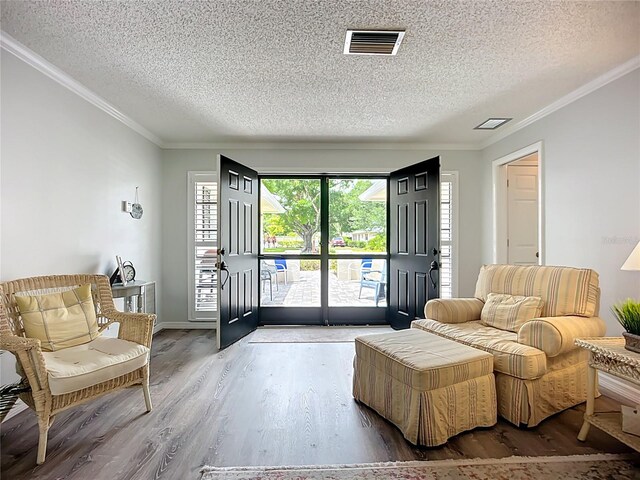 living area featuring a textured ceiling, ornamental molding, and wood finished floors