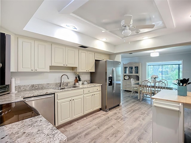 kitchen featuring appliances with stainless steel finishes, a sink, a raised ceiling, and a ceiling fan