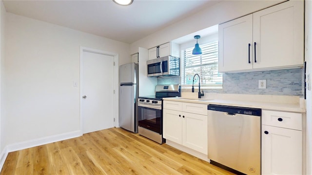 6710 S Juanita St, Tampa, FL 33616 - kitchen featuring a sink, stainless steel appliances, backsplash, and light wood-style flooring