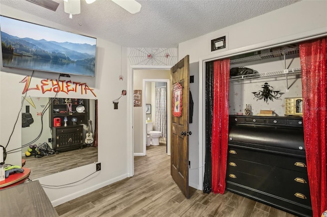 hall with wood finished floors, a textured ceiling, and baseboards