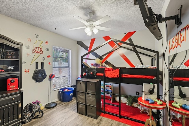 recreation room featuring wood finished floors, ceiling fan, a textured ceiling, and baseboards