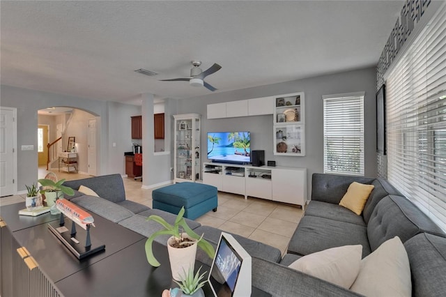 5914 Goldenbark Pl, Lithia, FL 33547 - living room with arched walkways, ceiling fan, light tile patterned floors, and stairs
