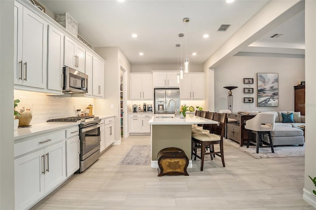 4329 Barletta Ct, Wesley Chapel, FL 33543 - kitchen with appliances with stainless steel finishes, decorative backsplash, a sink, a breakfast bar area, and recessed lighting