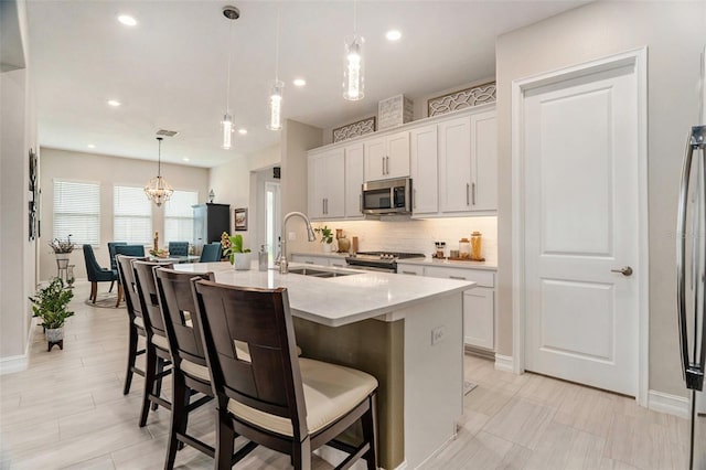 4329 Barletta Ct, Wesley Chapel, FL 33543 - kitchen featuring appliances with stainless steel finishes, a sink, tasteful backsplash, a kitchen bar, and an island with sink