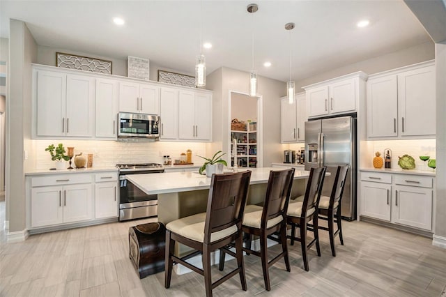 4329 Barletta Ct, Wesley Chapel, FL 33543 - kitchen with stainless steel appliances, light countertops, a kitchen island with sink, decorative backsplash, and white cabinetry