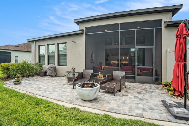 4329 Barletta Ct, Wesley Chapel, FL 33543 - rear view of property featuring a sunroom, a patio, stucco siding, and an outdoor living space with a fire pit
