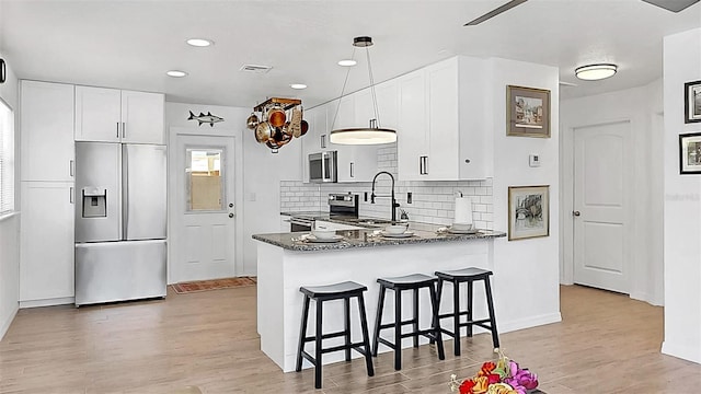 4735 W Oklahoma Ave, Tampa, FL 33616 - kitchen featuring appliances with stainless steel finishes, a sink, a kitchen bar, light wood-style floors, and tasteful backsplash