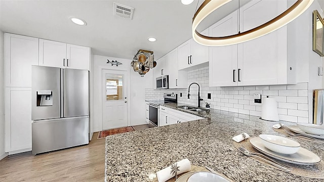 4735 W Oklahoma Ave, Tampa, FL 33616 - kitchen featuring appliances with stainless steel finishes, a sink, dark stone countertops, white cabinetry, and light wood finished floors