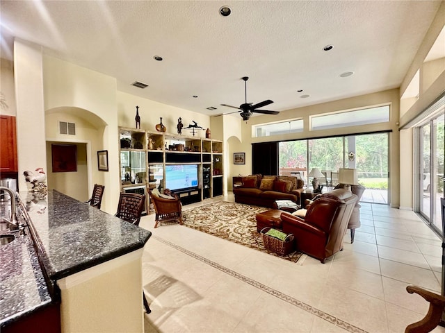 16343 Burniston Dr, Tampa, FL 33647 - living area featuring light tile patterned floors, a ceiling fan, a textured ceiling, and arched walkways