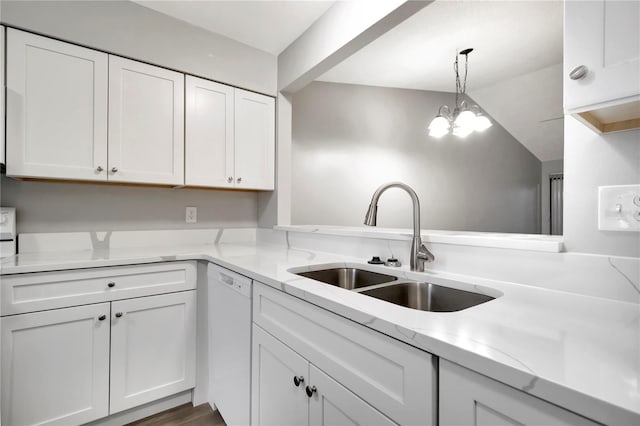 kitchen featuring white dishwasher, a sink, white cabinets, light stone counters, and decorative light fixtures