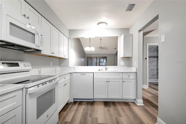 kitchen with white appliances, a sink, a chandelier, light wood finished floors, and light countertops