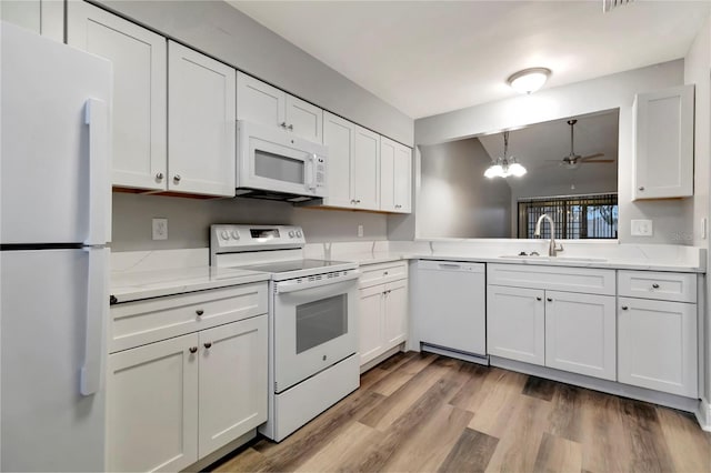 kitchen featuring white appliances, a sink, white cabinets, and light wood-style flooring
