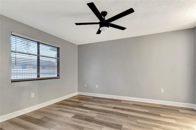 unfurnished room with a ceiling fan, wood finished floors, baseboards, and a textured ceiling