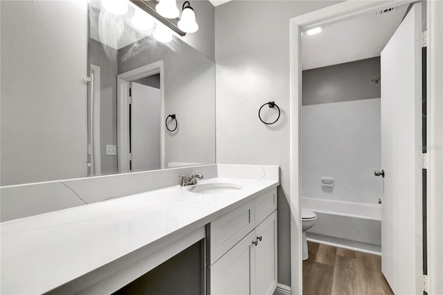full bath featuring wood finished floors, toilet, vanity, and a tub to relax in