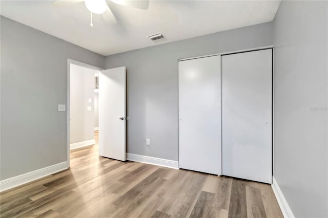 unfurnished bedroom featuring wood finished floors, baseboards, a closet, and ceiling fan