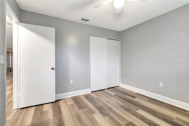unfurnished bedroom with wood finished floors, baseboards, a closet, and ceiling fan